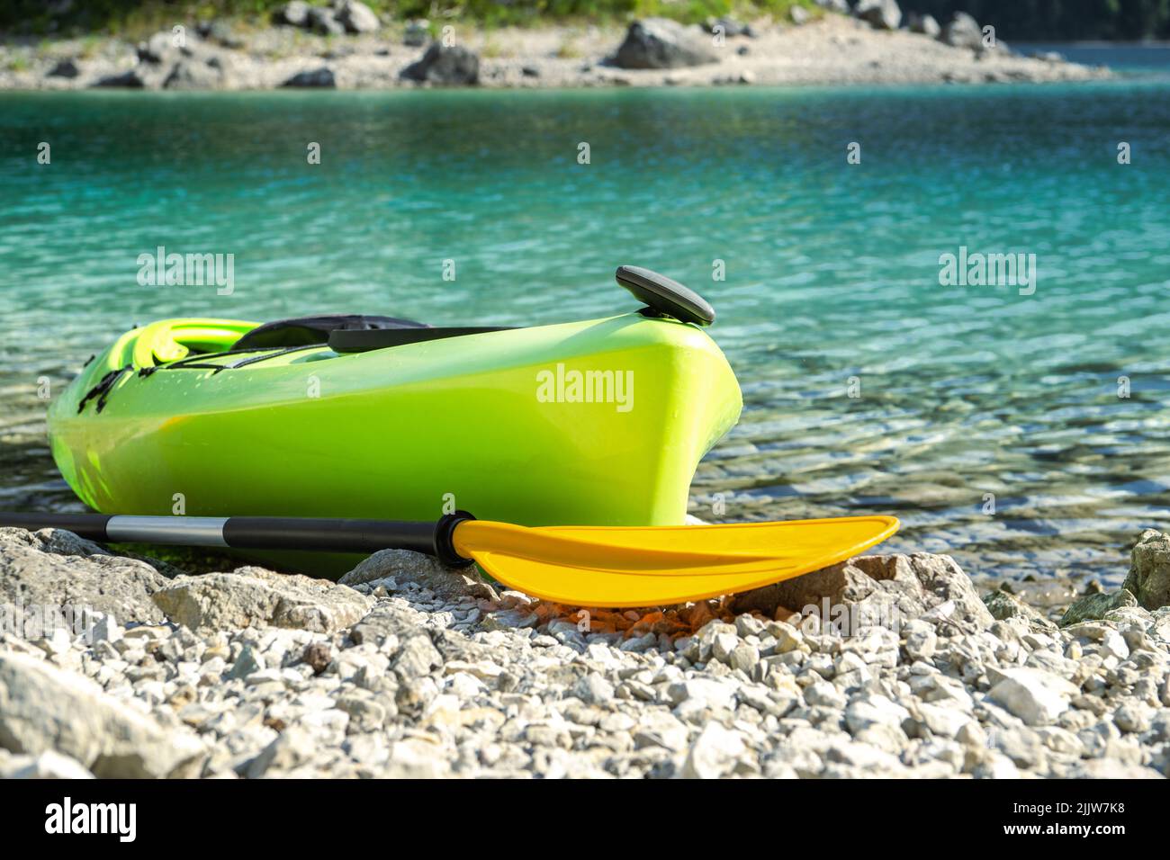 Kayak Green Touring sur une côte de Rocky Lake pendant une chaude journée d'été. Thème des sports nautiques. Banque D'Images