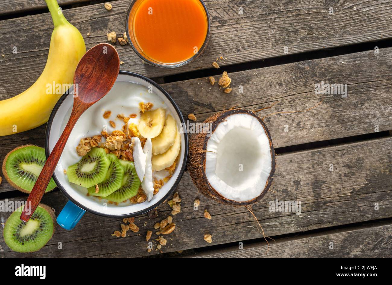 Yaourt à la noix de coco avec granola et fruits sur une table rustique en bois avec espace pour les copies nourriture végétarienne saine pour le petit-déjeuner Banque D'Images