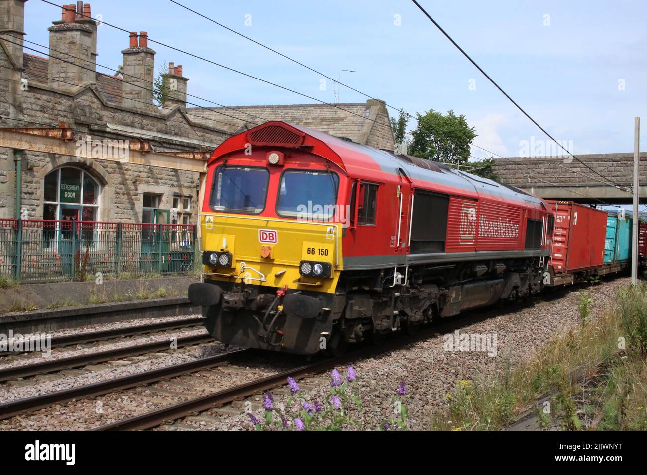 DB Cargo UK classe 66, 66150, en direction sud par Carnforth sur la ligne principale de la côte ouest le mercredi 27th juillet 2022 avec un train à conteneurs. Banque D'Images