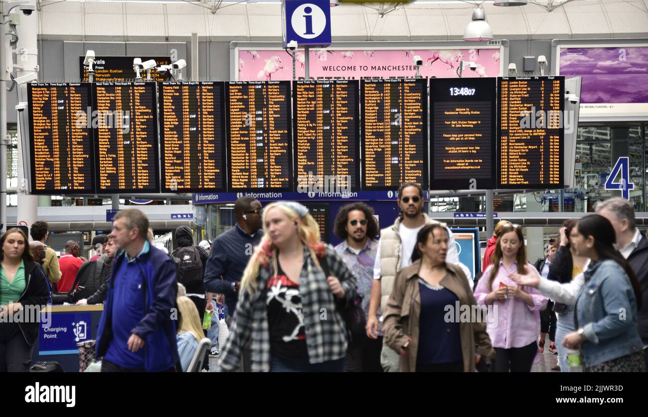 Les passagers du train et un panneau d'information sur les horaires des trains à la gare de Piccadilly, Manchester, Greater Manchester, Angleterre, Royaume-Uni, Îles britanniques. Le syndicat Aslef a déclaré aujourd'hui que les conducteurs de train de neuf compagnies de chemin de fer vont faire grève pendant encore 24 heures sur 13 août 2022, plus de salaire. Aslef affirme que les entreprises n'ont pas réussi à faire une offre de salaire pour aider les membres à suivre le rythme de l'augmentation du coût de la vie. Banque D'Images