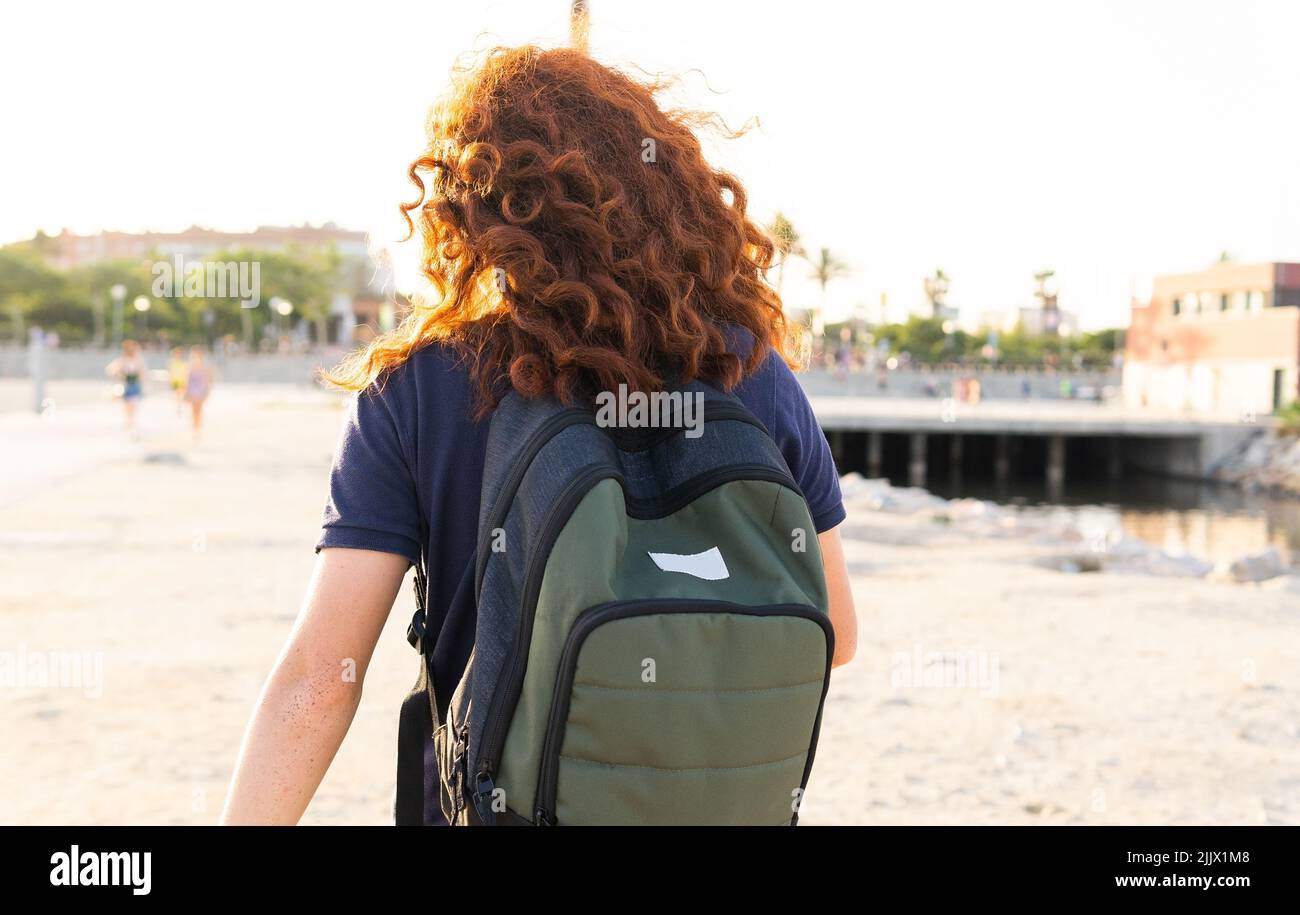 Vue arrière de la jeune femme avec tête rouge et sac à dos contre la ville Banque D'Images