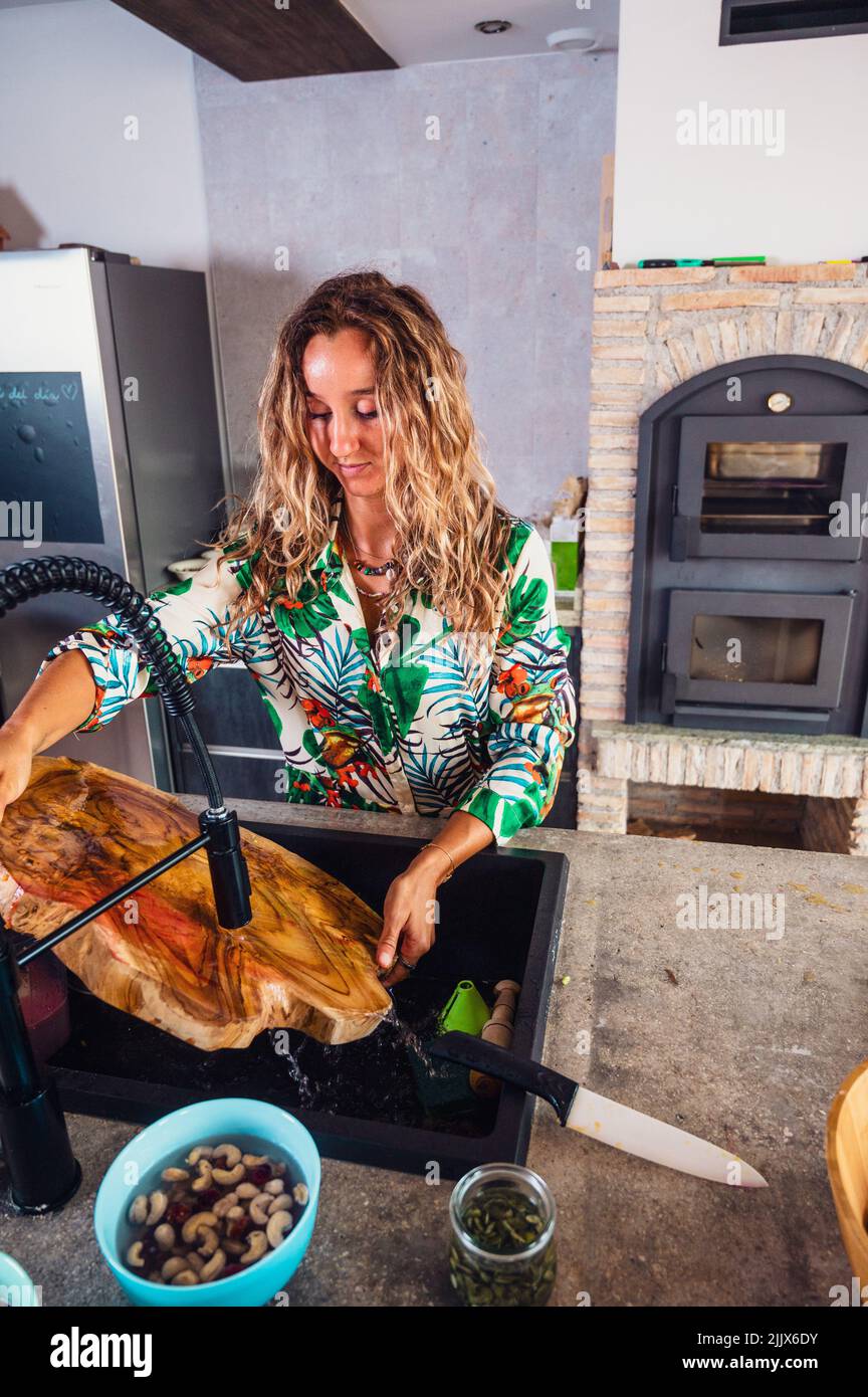 Par dessus la femelle blonde enlever le jus de betterave de la dalle de bois après la préparation de plat vegan dans la cuisine à la maison Banque D'Images