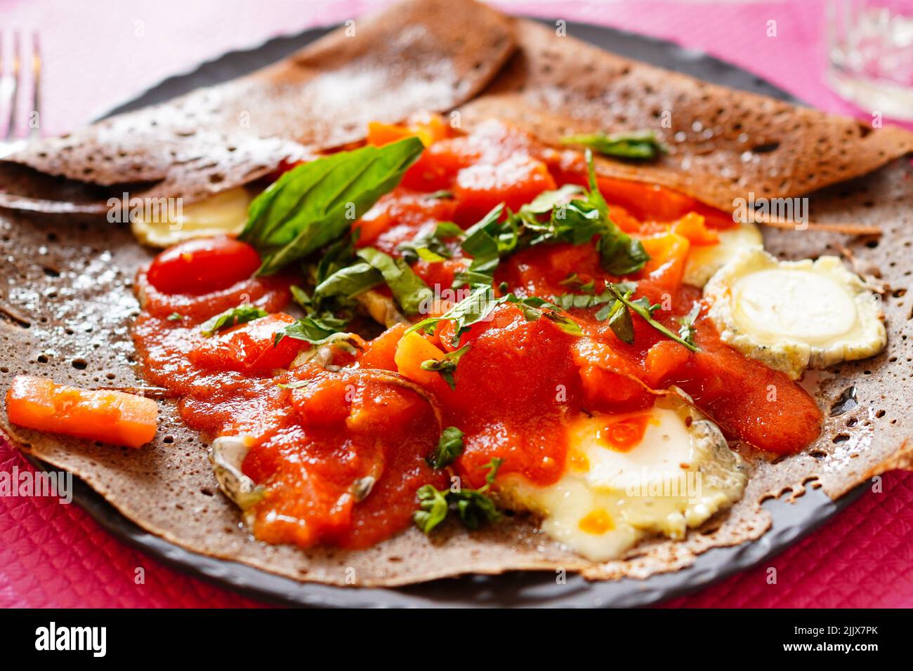 Gros plan de la crêpe française de sarrasin Galette avec tomates fraîches et fromage de chèvre, basilic Banque D'Images