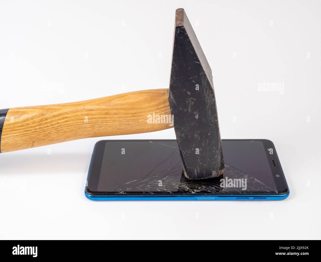 Un marteau doté d'une poignée en bois casse un smartphone. Banque D'Images