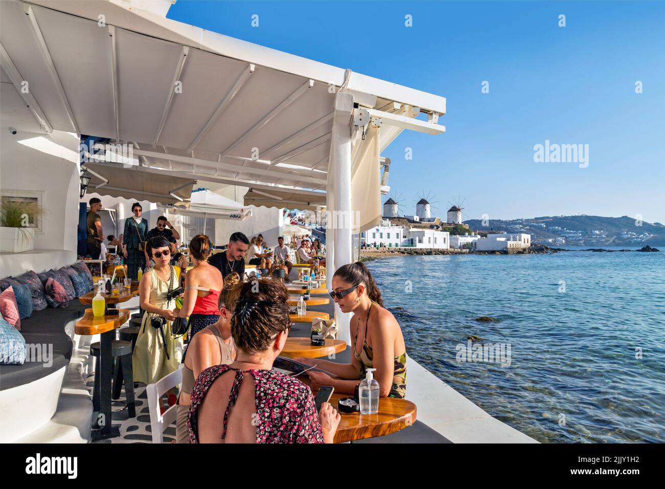 Un moment de café dans la célèbre « petite Venise » sur l'île Chora de Mykonos avec les moulins à vent en arrière-plan. Cyclades, Mer Egéé, Grèce. Banque D'Images