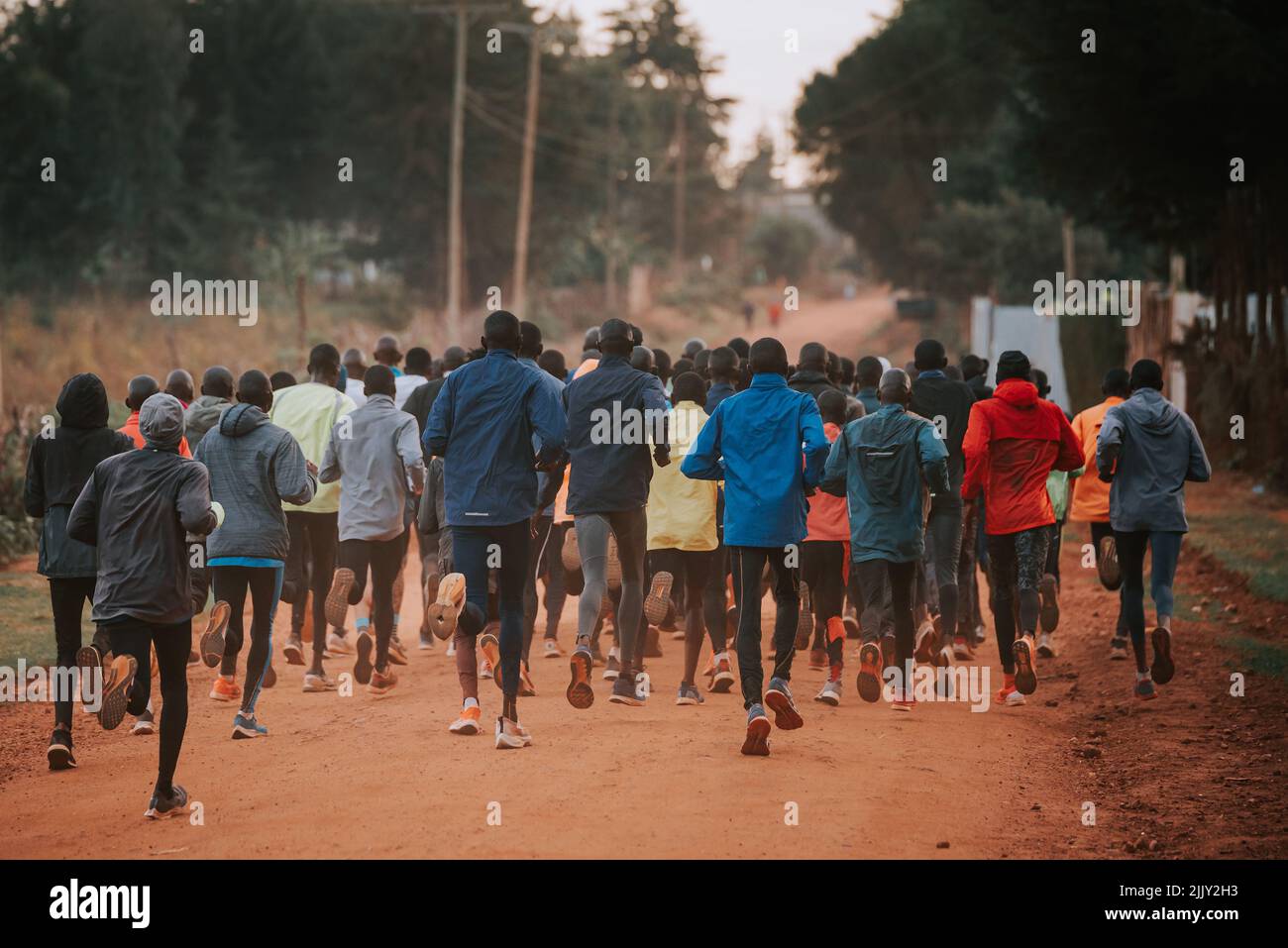 Formation de groupe au Kenya. Un grand groupe de coureurs kenyans se prépare à la course. Les coureurs professionnels d'endurance et de marathon courent sur le sol rouge o Banque D'Images
