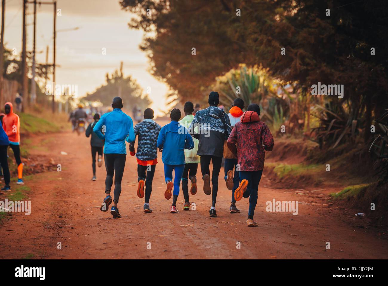 Formation de groupe au Kenya. Un grand groupe de coureurs kenyans se prépare à la course. Les coureurs professionnels d'endurance et de marathon courent sur le sol rouge o Banque D'Images