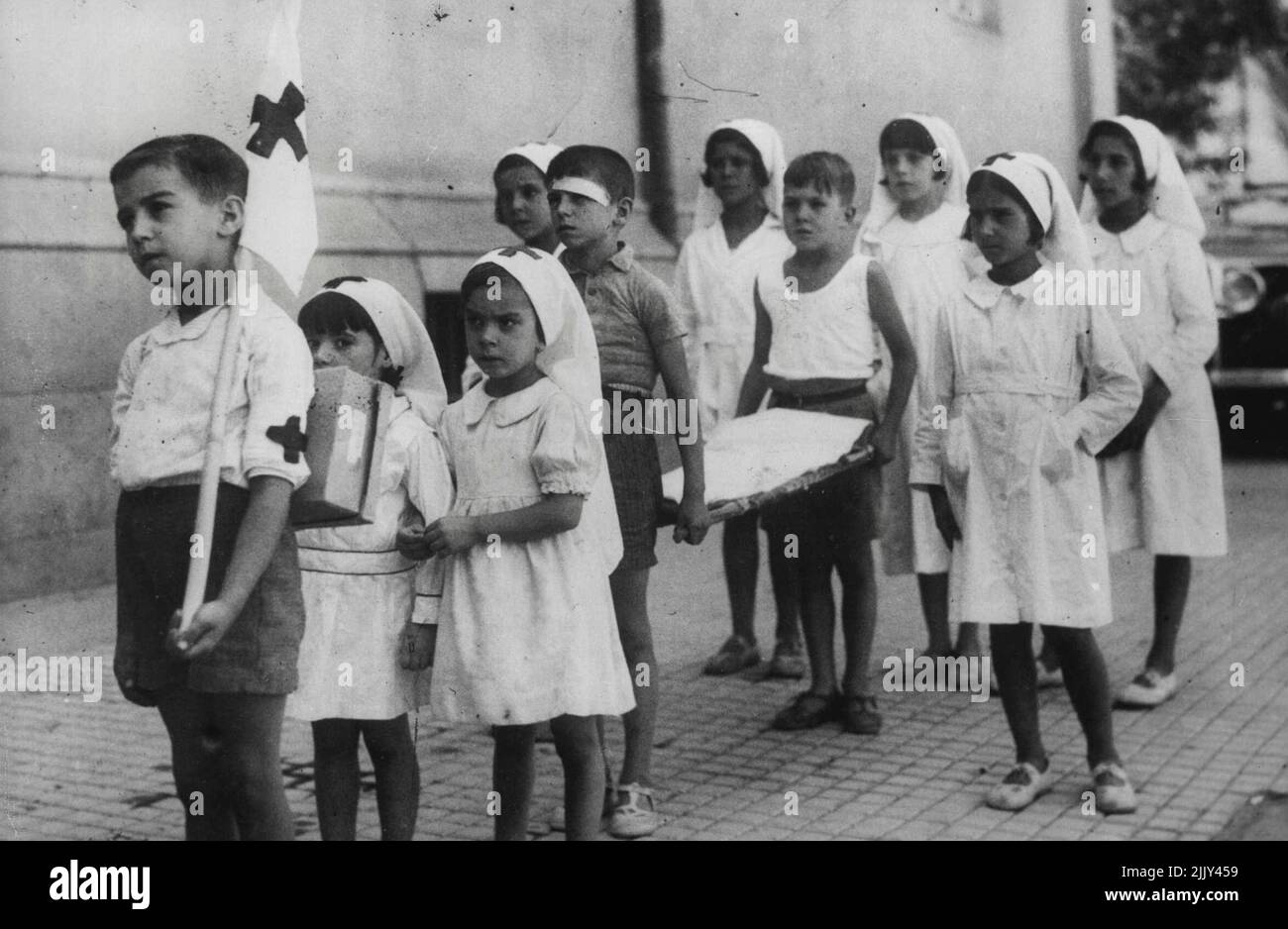 Les petits enfants jouent à la guerre civile comme les rebelles menace Madrid -- les garçons et les filles 'Croix Rouge' travailleurs prêts avec leur civière à Madrid. Le brancard - support à l'avant a déjà une bande de plâtre collant. Les jeunes enfants de Madrid mènent leur propre 'guerre' contre les rebelles. Tandis que leurs parents plus âgés se rallient à la défense de la capitale, les enfants ont leur propre armée avec des unités 'blessés' et Croix-Rouge. 22 octobre 1936. (Photo de Planet News). Banque D'Images