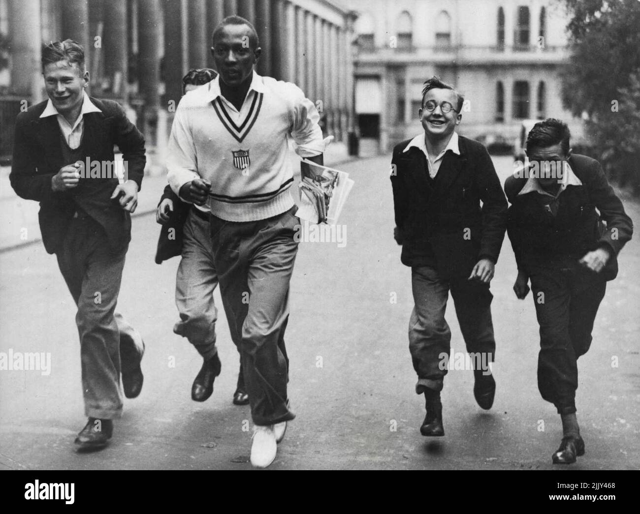 Les athlètes olympiques américains de Londres où ils participeront à un concours d'athlétisme contre une équipe anglaise au stade de White City, sur 15 août. Jesse Owens, le célèbre coureur américain, montre à quelques jeunes messagers « comment faire ». 14 août 1936. (Photo de Sport & General Press Agency, Limited). Banque D'Images