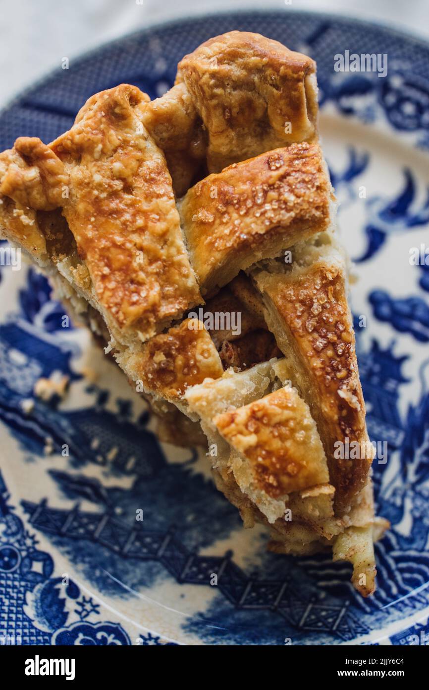 une seule tranche de tarte aux amandes de pomme en croûte de treillis sur une assiette bleue et blanche Banque D'Images