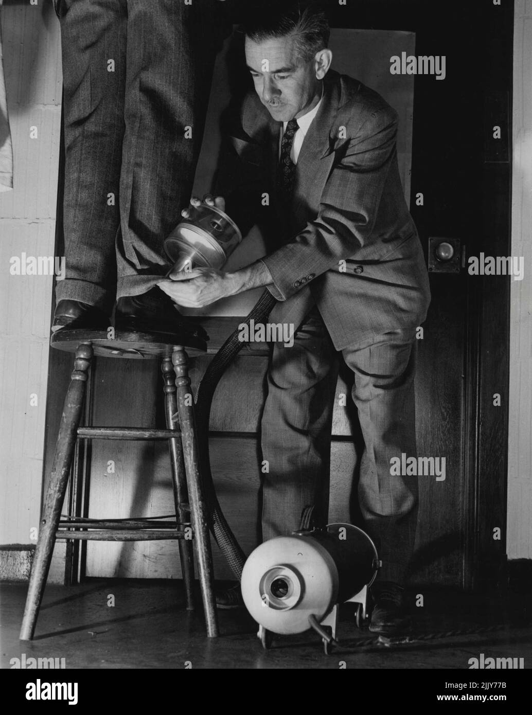 Micro-COP. (3) de l'ensemble de cinq -- le professeur Paul Kirk dans sa recherche de balayage d'un suspect porte une attention particulière aux manchettes de pantalon, poches et sacs à main pour femmes. Dans les peluches et la poussière, il recherche un brin de cheveux, de laine, de soie ou de coton qui peut relier le suspect à la victime. 30 janvier 1948. (Photo par Acme photo Service). Banque D'Images