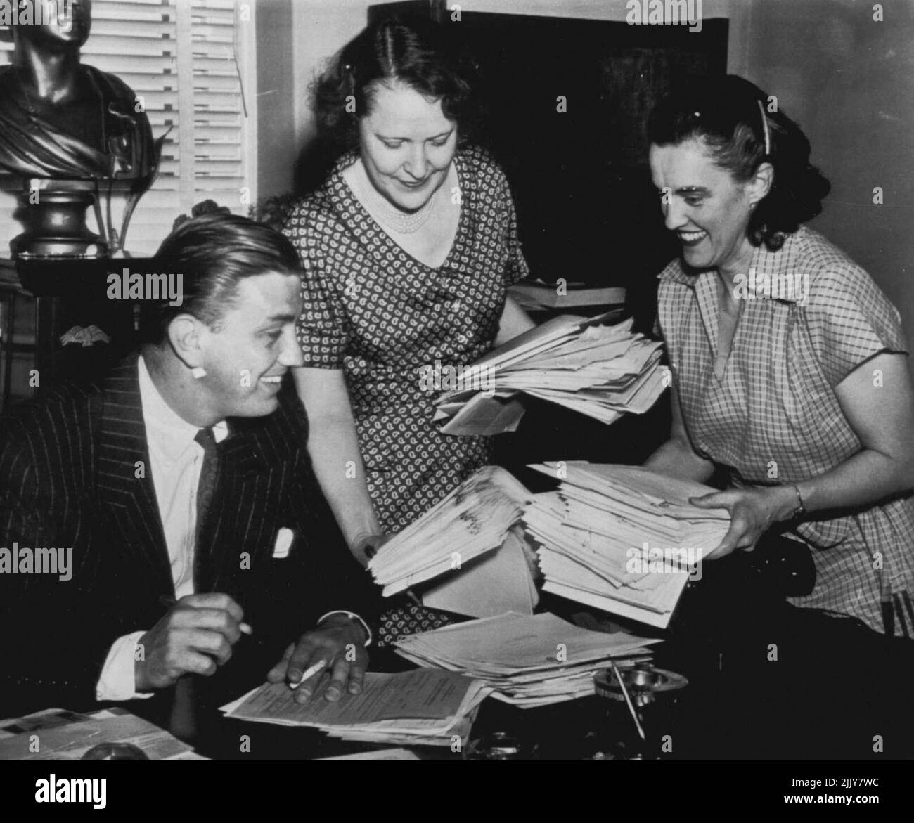 Membre du Congrès au travail - Freshman membre du Congrès Franklin D. Roosevelt Jr., de New York, traitant un certain travail aujourd'hui dans son premier jour à son bureau de maison. Les documents, en attente de sa signature, sont remis à Roosevelt par les secrétaires Mme Lillian de Sales(Left) et Veva Murphy. Le jeune Roosevelt a prêté serment hier en tant que membre de la maison. 15 juin 1949. (Photo par AP Wirephoto). Banque D'Images Membre du Congrès au travail - Freshman membre du Congrès Franklin D. Roosevelt Jr., de New York, traitant un certain travail aujourd'hui dans son premier jour à son bureau de maison. Les documents, en attente de sa signature, sont remis à Roosevelt par les secrétaires Mme Lillian de Sales(Left) et Veva Murphy. Le jeune Roosevelt a prêté serment hier en tant que membre de la maison. 15 juin 1949. (Photo par AP Wirephoto). Banque D'Images