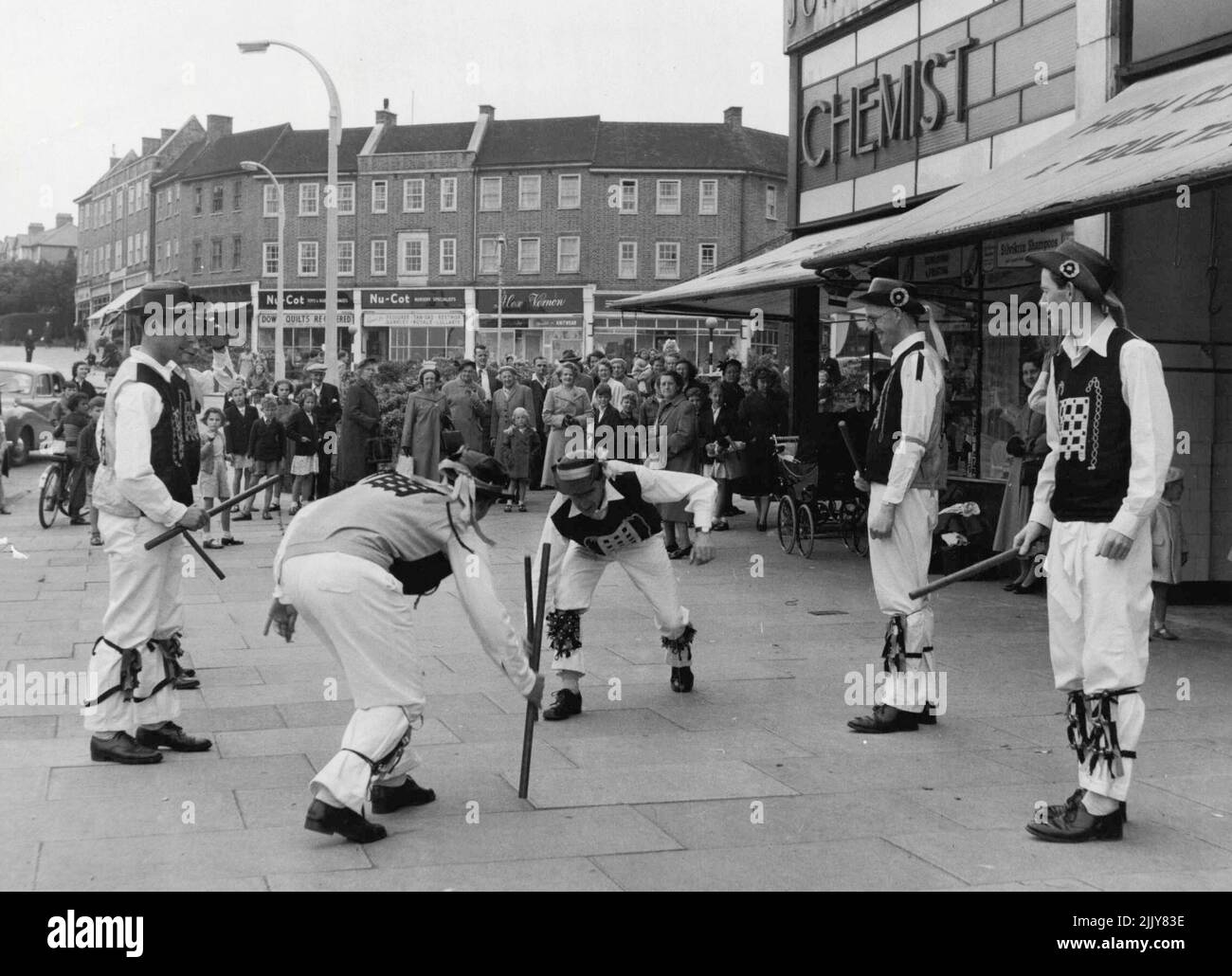 Vous avez l'habitude du voir sur le vert du village. Mais maintenant qu'il n'y a pas tant de greens de village au sujet de cette équipe de danseurs Morris de Westminster, il doit se contenter de la chaussée pour leur exposition de danse dans un centre commercial de Barnett est. Parmi les danseurs, dont le siège est à Millbank à Londres, on compte un plombier, un électricien, un enseignant, des artistes et un producteur de variétés. 22 juin 1955. (Photo par Daily Mirror). Banque D'Images