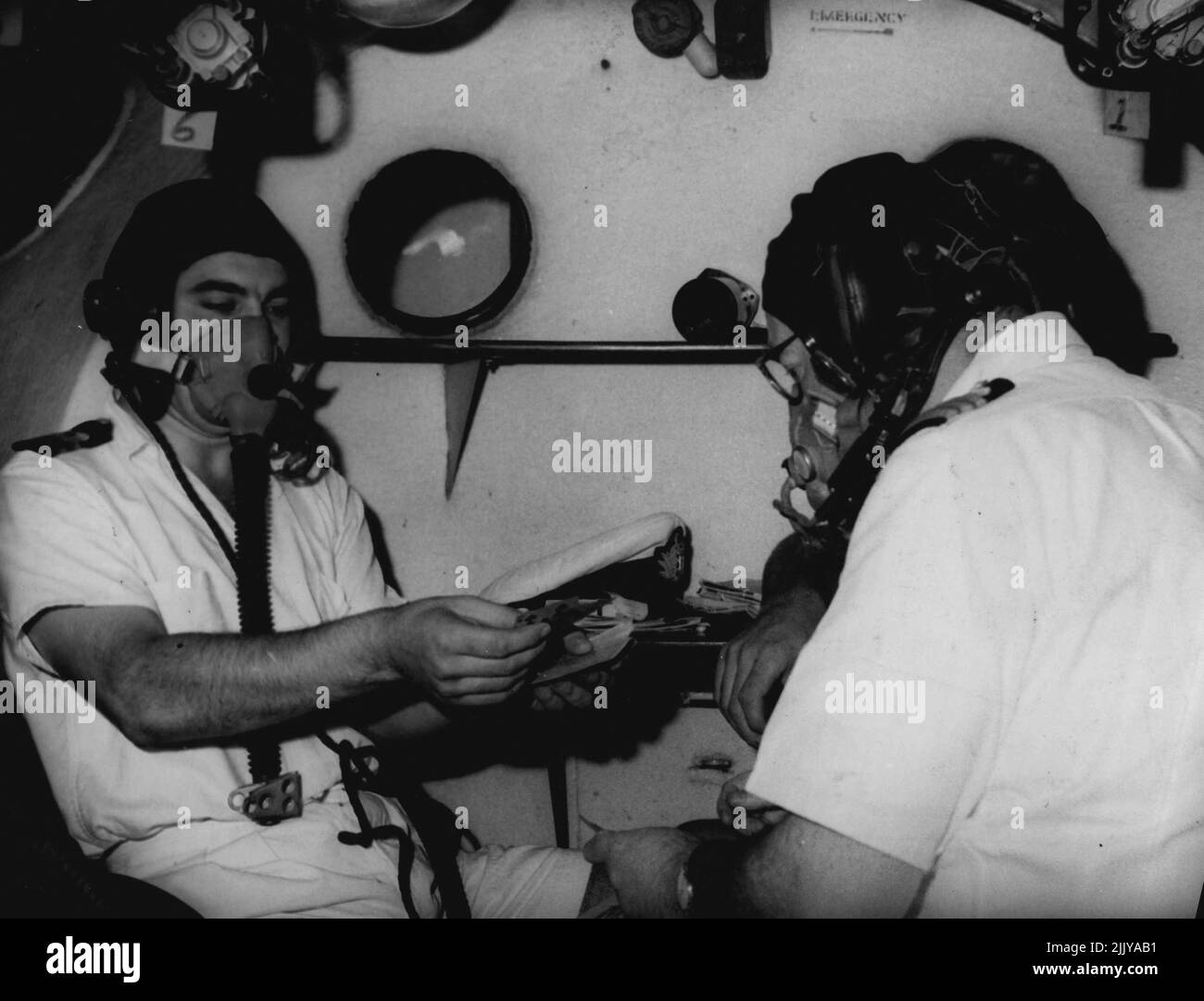 Le Lt K. Suriano, facultés mentales perdues par manque d'oxygène tente de traiter des cartes au chirurgien-commandant R. COPlanS, à droite, pendant un essai en hauteur dans une chambre de compression. 23 mars 1955. Banque D'Images