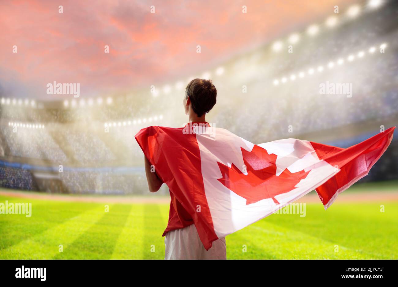 Un supporter du football canadien au stade. Les fans canadiens sur le terrain de football en regardant l'équipe jouer. Groupe de supporters avec drapeau et maillot national Banque D'Images