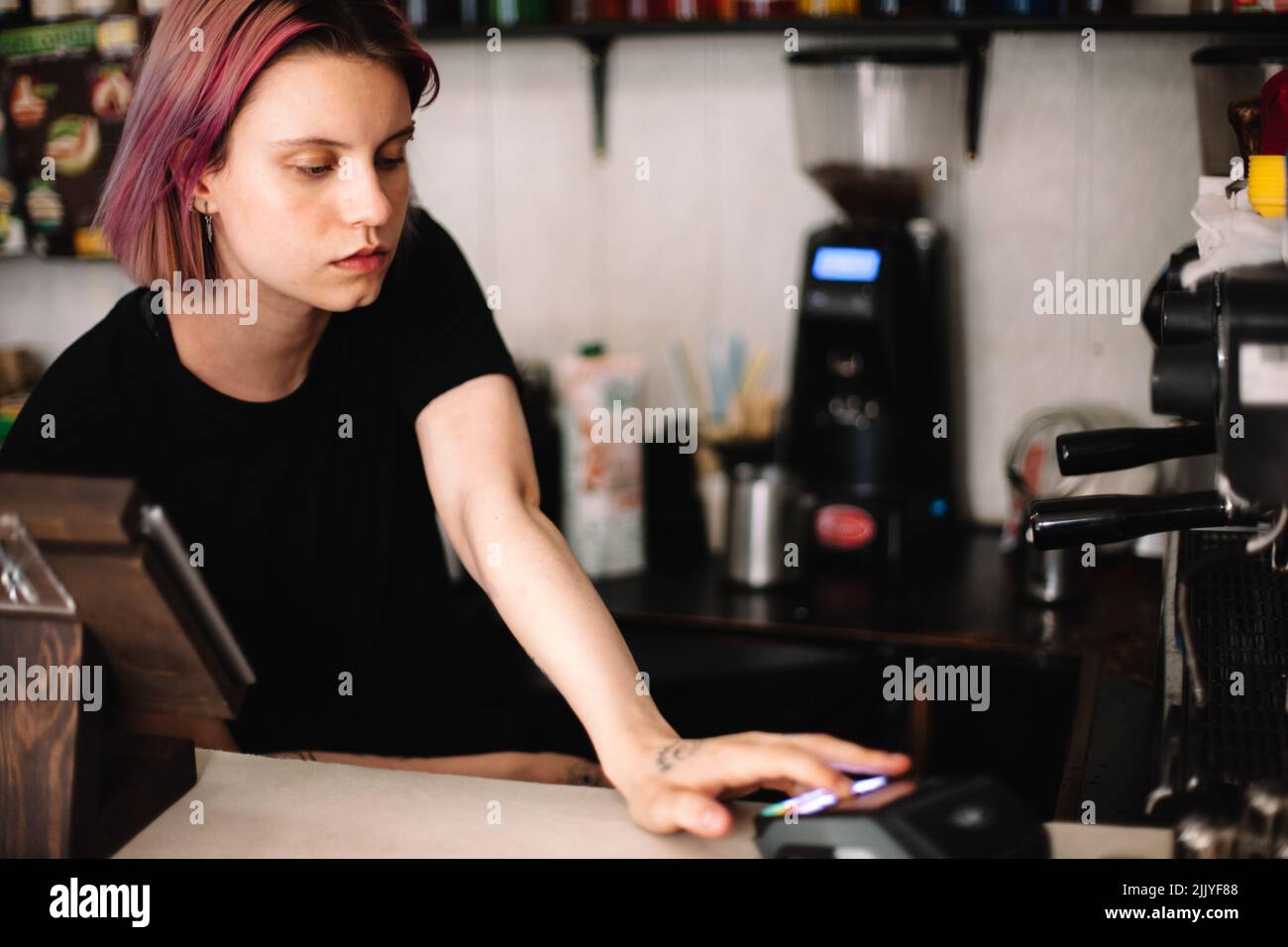 Jeune barista femme travaillant au comptoir de caisse du café Banque D'Images