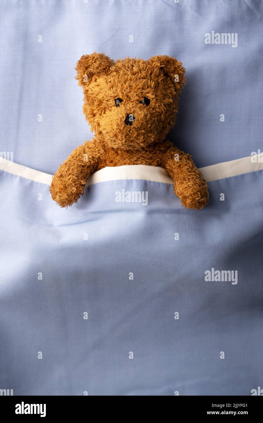 Ours en peluche brun posé sur un lit bleu. Concept de médecine pédiatrique et pédiatrique Banque D'Images