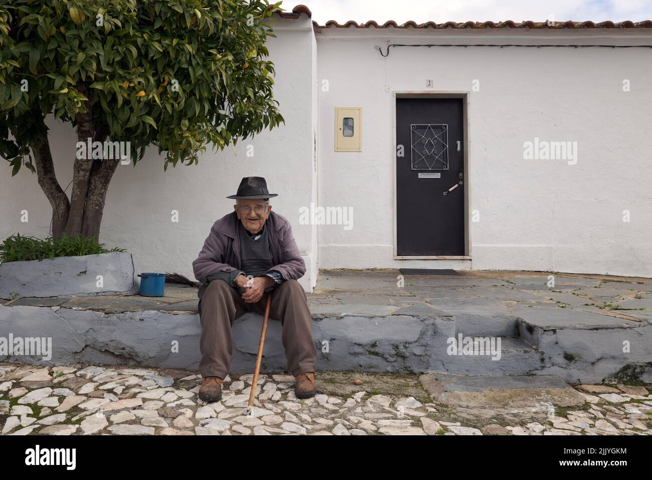Vieil homme âgé assis devant sa porte Banque D'Images