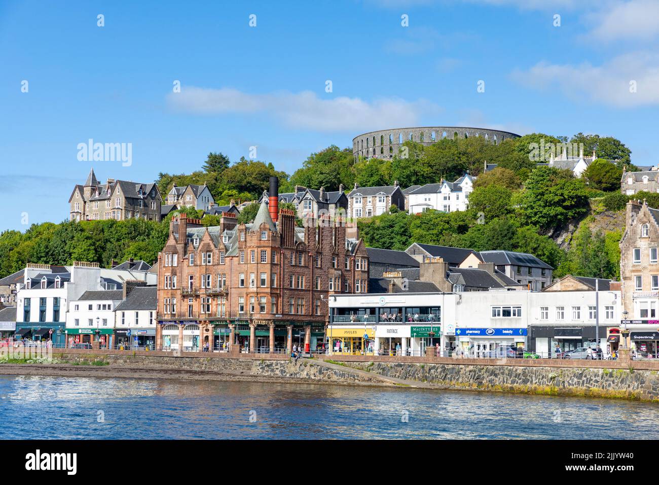 Centre-ville d'Oban avec la tour folle de McCaig, bâtiments de rue élevés sur George Street, Écosse, Royaume-Uni en été 2022 avec ciel bleu Banque D'Images