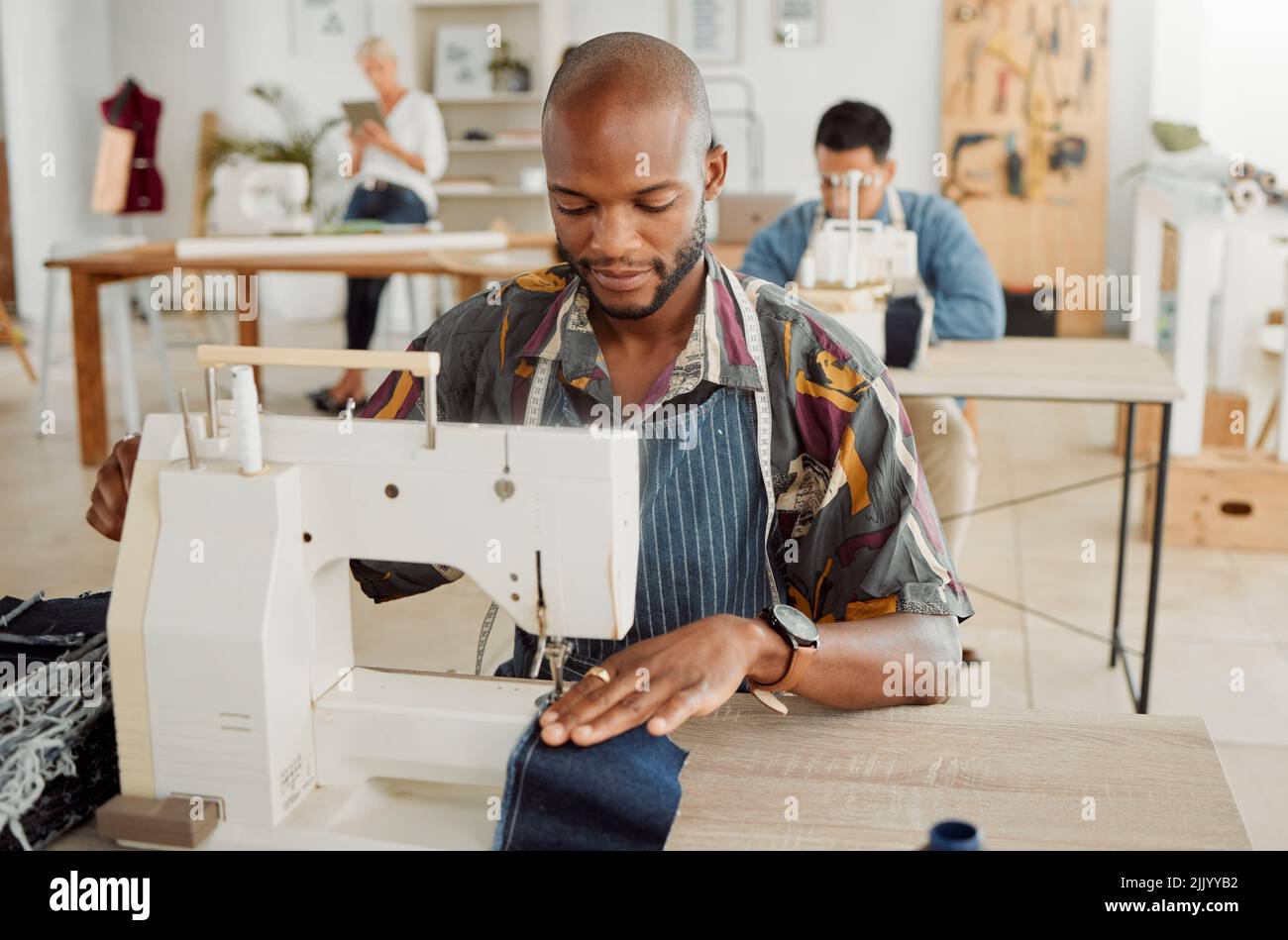 Dessinateur de mode, jeune homme et étudiant créateur dans un atelier pour coudre des vêtements et des vêtements. Travailleur d'usine, sur mesure et apprenti apprentissage de la couture Banque D'Images