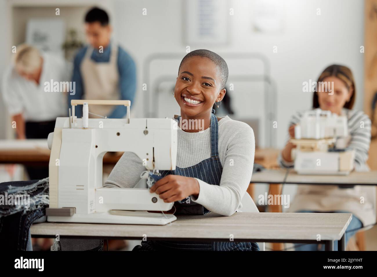 Portrait d'un designer de mode noir heureux travaillant sur des vêtements dans un atelier. Divers groupes d'étudiants effectuant un stage dans une usine de vêtements Banque D'Images