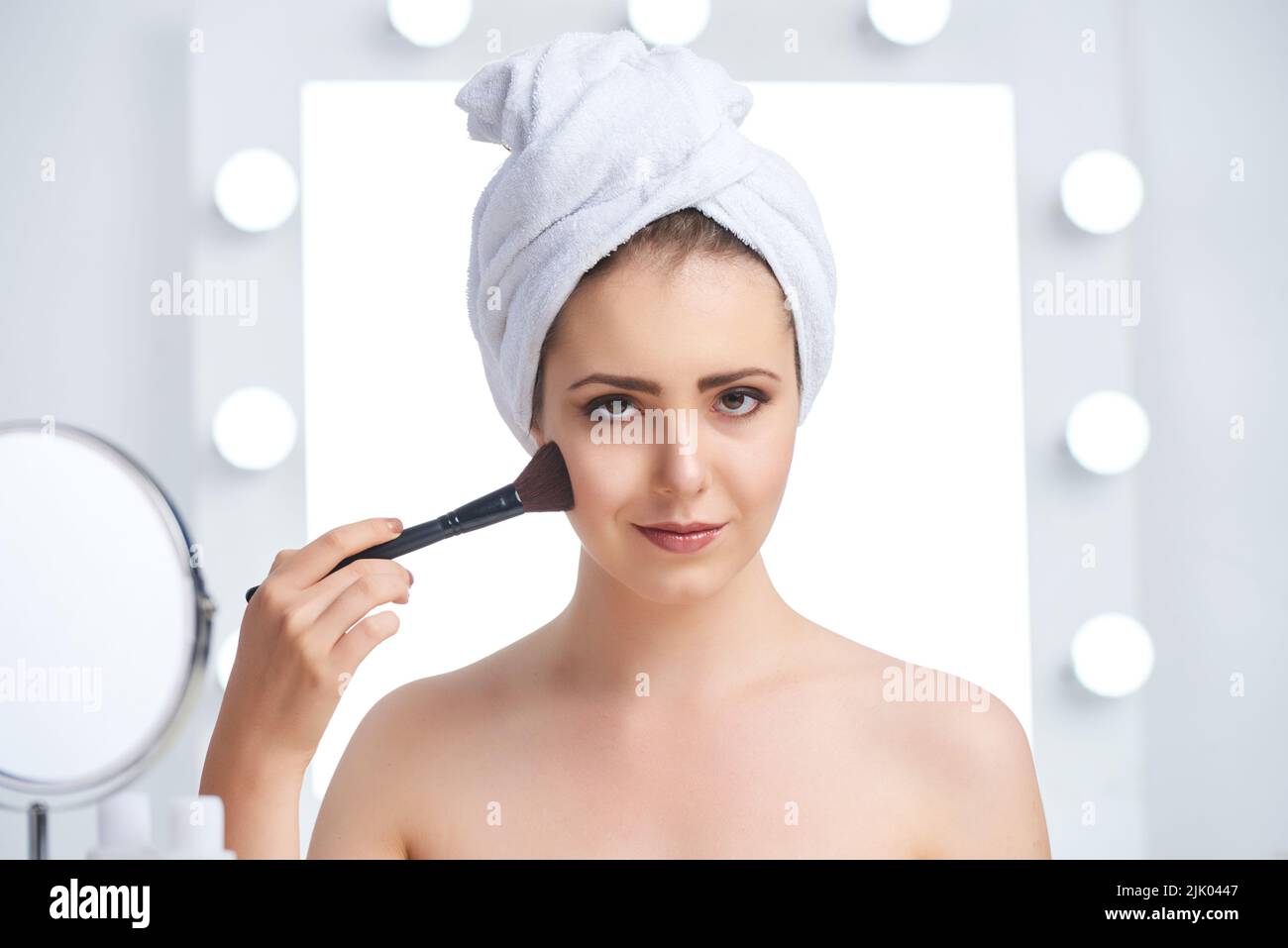 Magnifique jeune femme appliquant le maquillage le matin Banque D'Images
