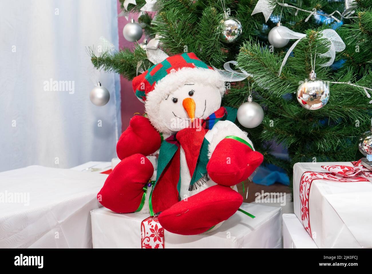 Un bonhomme de neige joyeux s'assoit sur des cadeaux sous l'arbre de Noël.  Conception d'hiver des locaux de l'école pour enfants Photo Stock - Alamy
