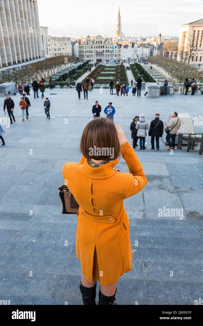 Dame dans un manteau orange photographiant le paysage urbain de Bruxelles du Mont des Arts Banque D'Images