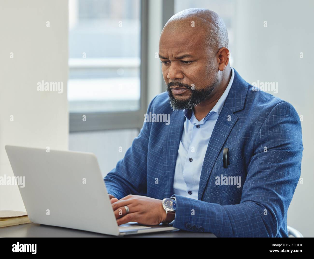 Les e-mails font partie de la tâche. Un homme d'affaires mûr et beau assis seul dans son bureau et utilisant son ordinateur portable. Banque D'Images
