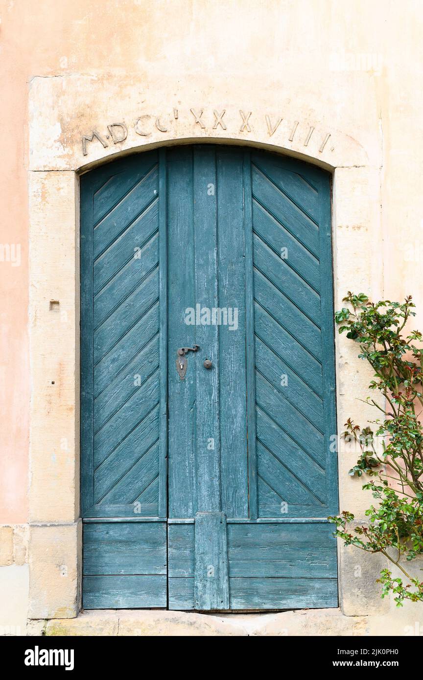 Une photo verticale d'une ancienne maison avec une porte en bois bleu et une inscription latine Banque D'Images