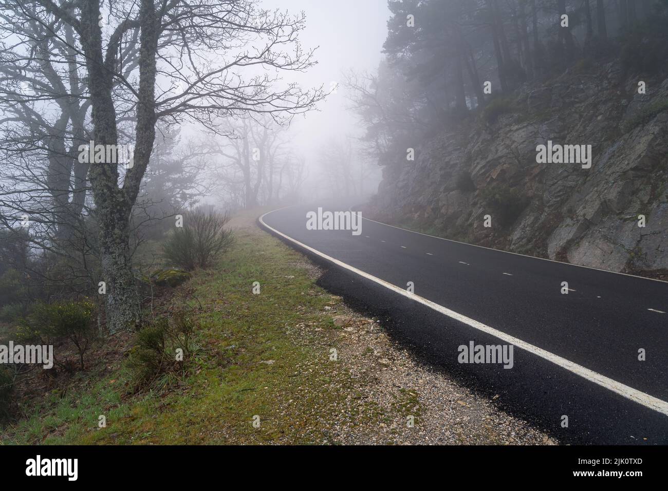 route de montagne courbée lors d'une journée brumeuse avec une très faible visibilité. Morcuera, Espagne. Banque D'Images