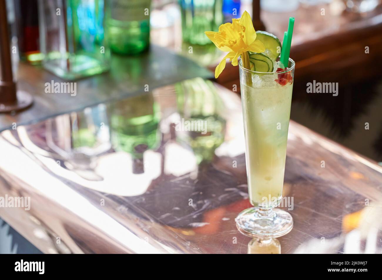 Un grand cocktail vert, garni de concombre et d'une fleur de jonquille Banque D'Images