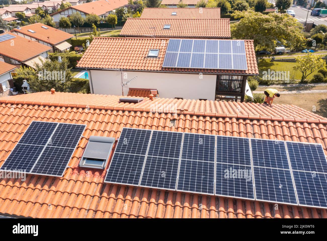 Travailleur installant des panneaux solaires sur un toit. Vue de drone. 4K. Navarre, Espagne, Europe. Concepts d'environnement et de technologie. Banque D'Images