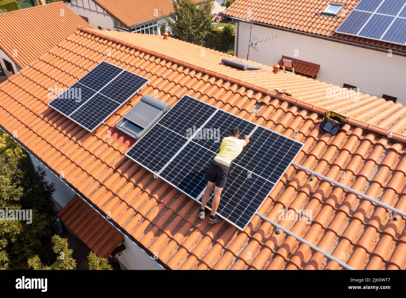 Travailleur installant des panneaux solaires sur un toit. Vue de drone. 4K. Navarre, Espagne, Europe. Concepts d'environnement et de technologie. Banque D'Images