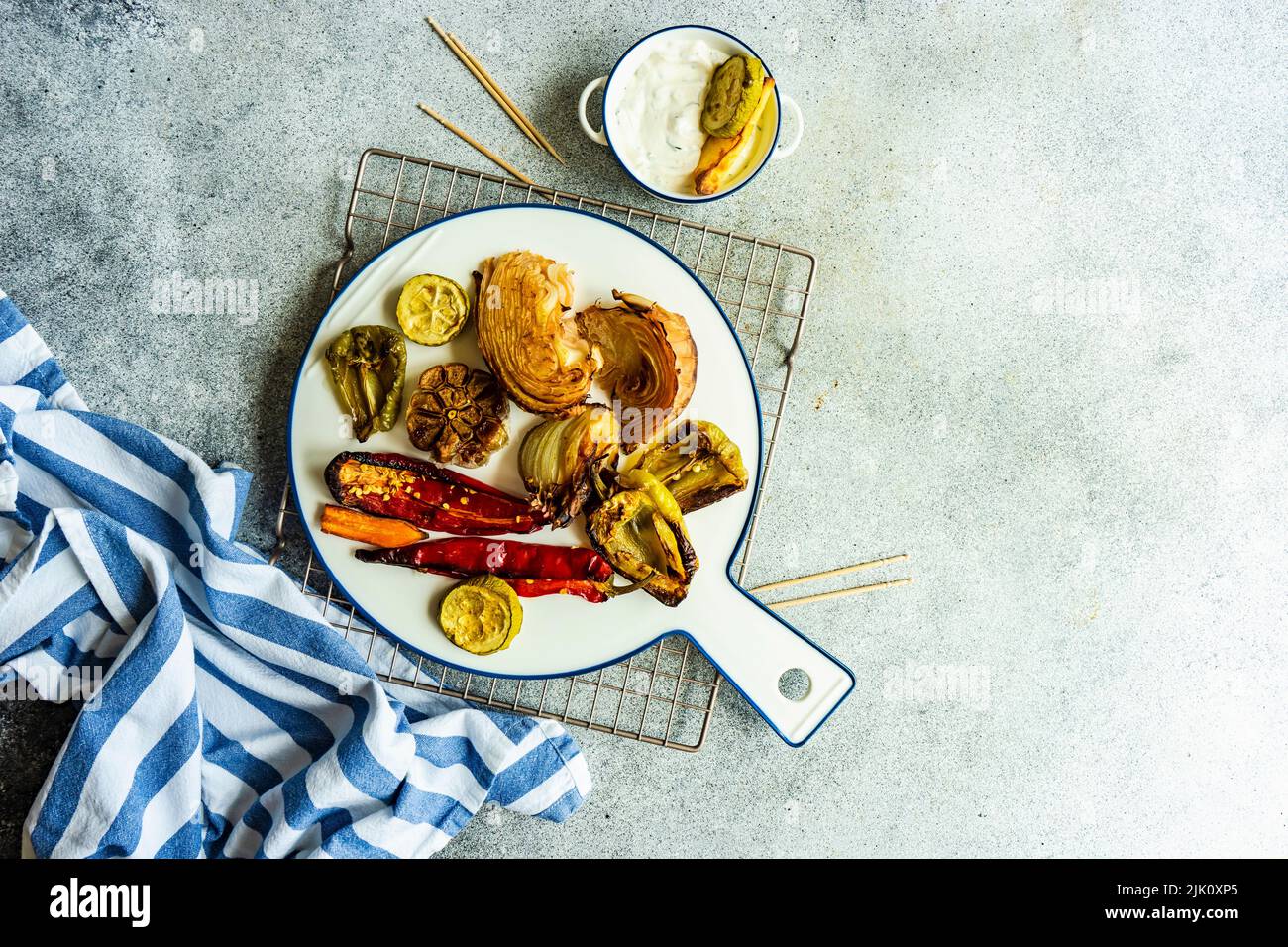 Un dîner sain avec une variété de légumes barbecue servi sur de la vaisselle en céramique avec une sauce à la crème aigre Banque D'Images