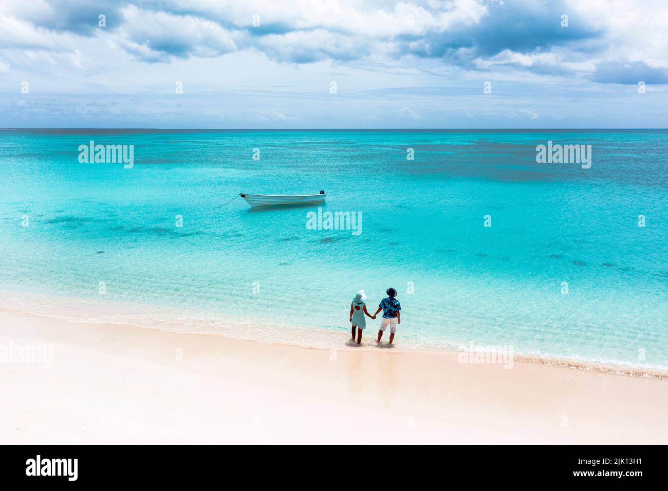 Homme et femme tenant la main sur une plage tropicale en admirant la mer cristalline, vue aérienne, Antigua-et-Barbuda, Antilles, Caraïbes Banque D'Images