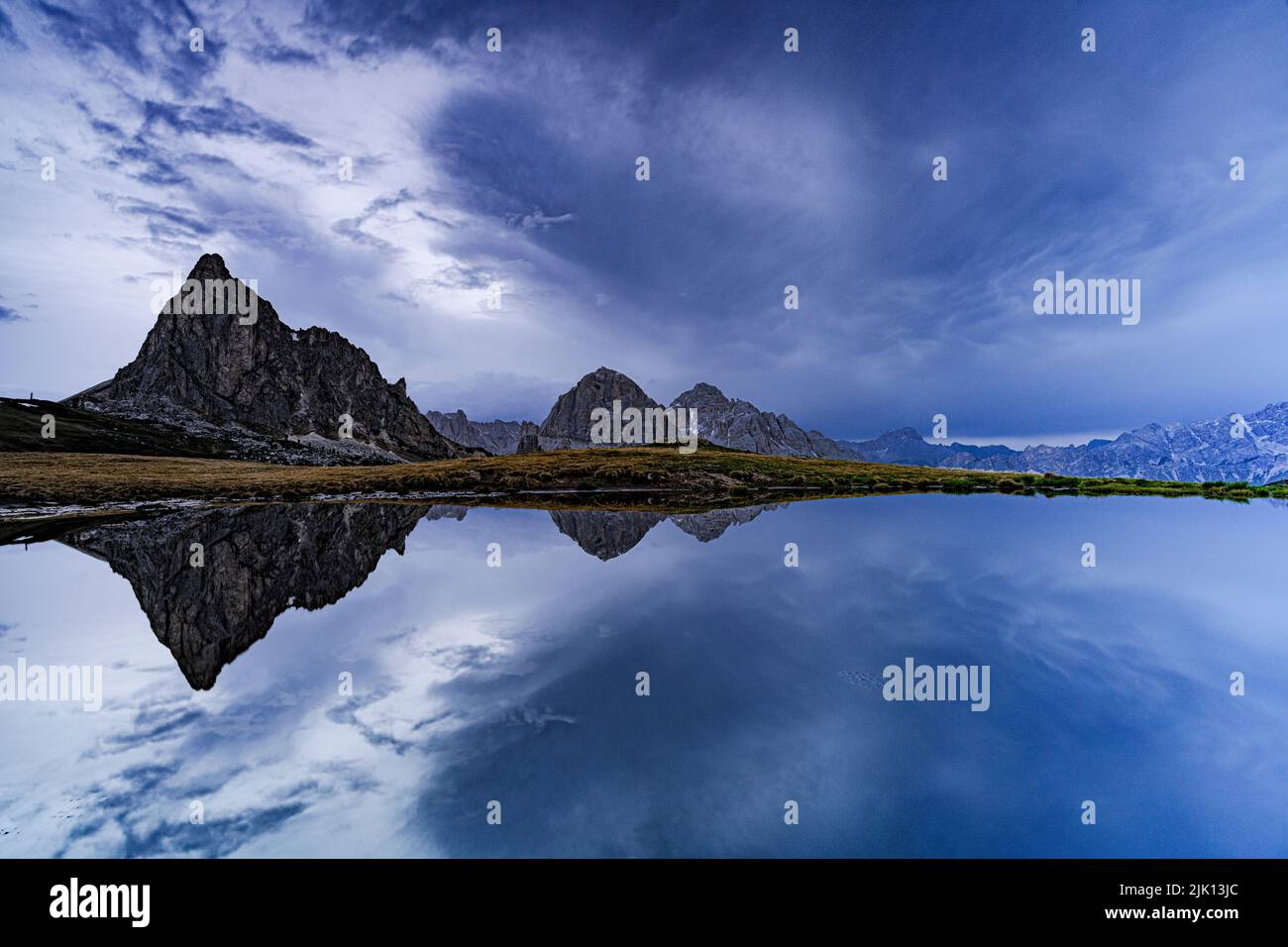 RA Gusela et Tofane sommets de montagne reflétés dans l'eau sous le ciel nuageux au crépuscule, col de Giau, Dolomites, Vénétie, Italie, Europe Banque D'Images