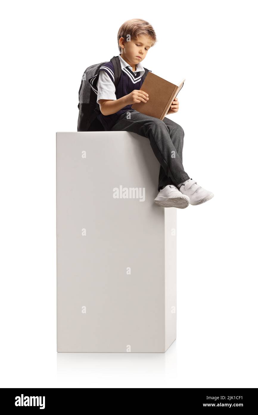 Élève assis sur une grande colonne blanche et lisant un livre isolé sur fond blanc Banque D'Images
