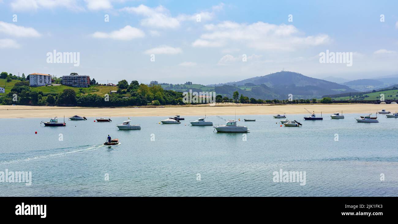 Vue sur la mer avec plage de sable blanc, bateaux et montagnes vertes en arrière-plan. Suances Santander. Banque D'Images
