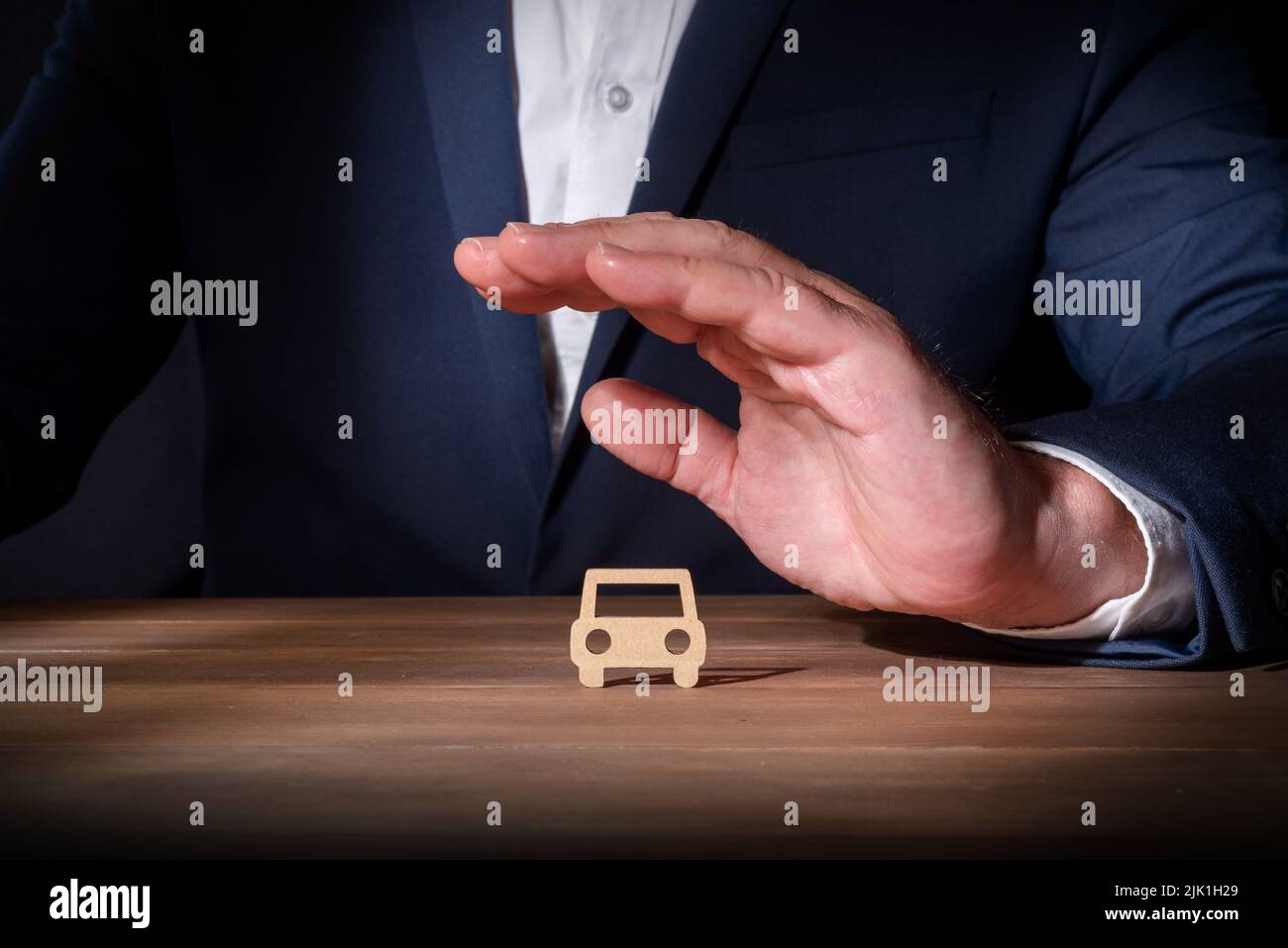 Professionnel de l'assurance couvrant une voiture découpée en carton avec sa main. Assurance véhicule complète. Protection contre les événements imprévus sur Banque D'Images