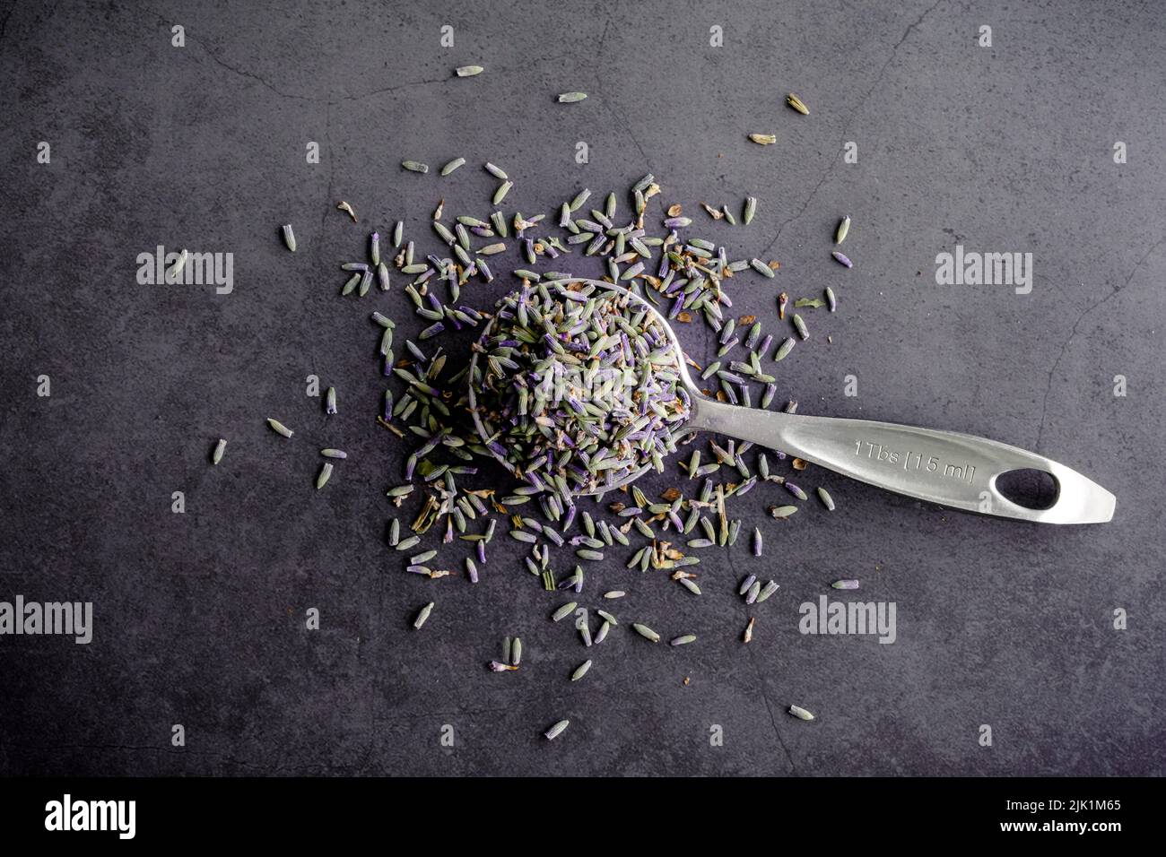 Lavande culinaire séchée vue d'en haut : une cuillère de mesure remplie de fleurs de lavande séchées Banque D'Images