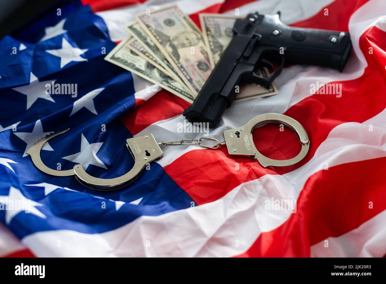 Menottes de police, dollars et une arme sur le drapeau des États-Unis, gros plan Banque D'Images