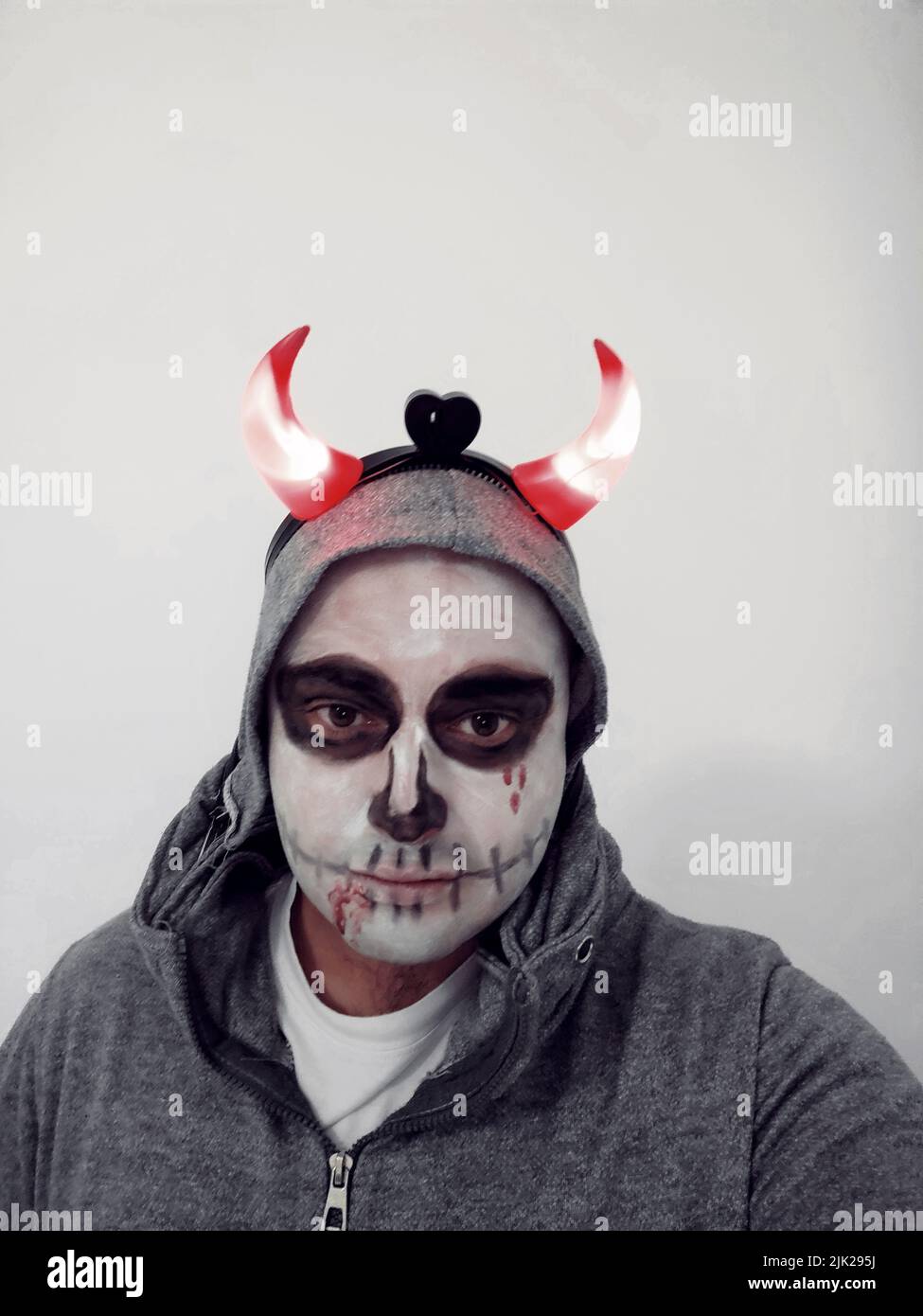 Un jeune homme avec un crâne peint sur son visage sur fond blanc. Célébration du jour des morts Banque D'Images