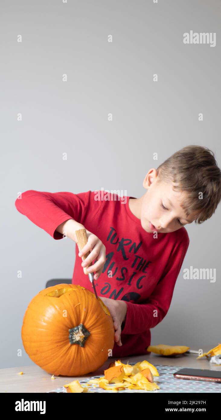 Garçon occupé à sculpter une citrouille jack-o-lanterne pour Halloween - enlever les graines Banque D'Images