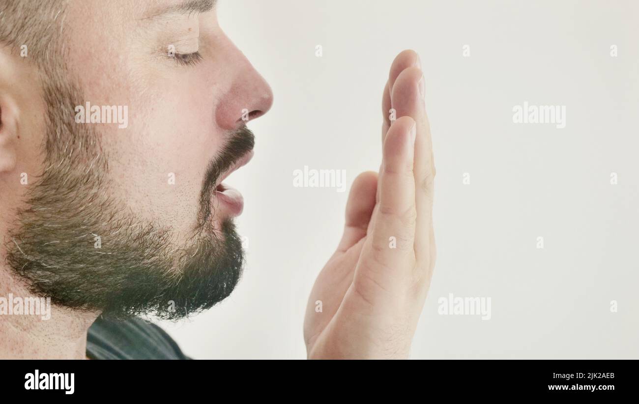 Mauvaise respiration. Le concept de l'halitose. Un jeune homme vérifie son souffle avec sa main Banque D'Images