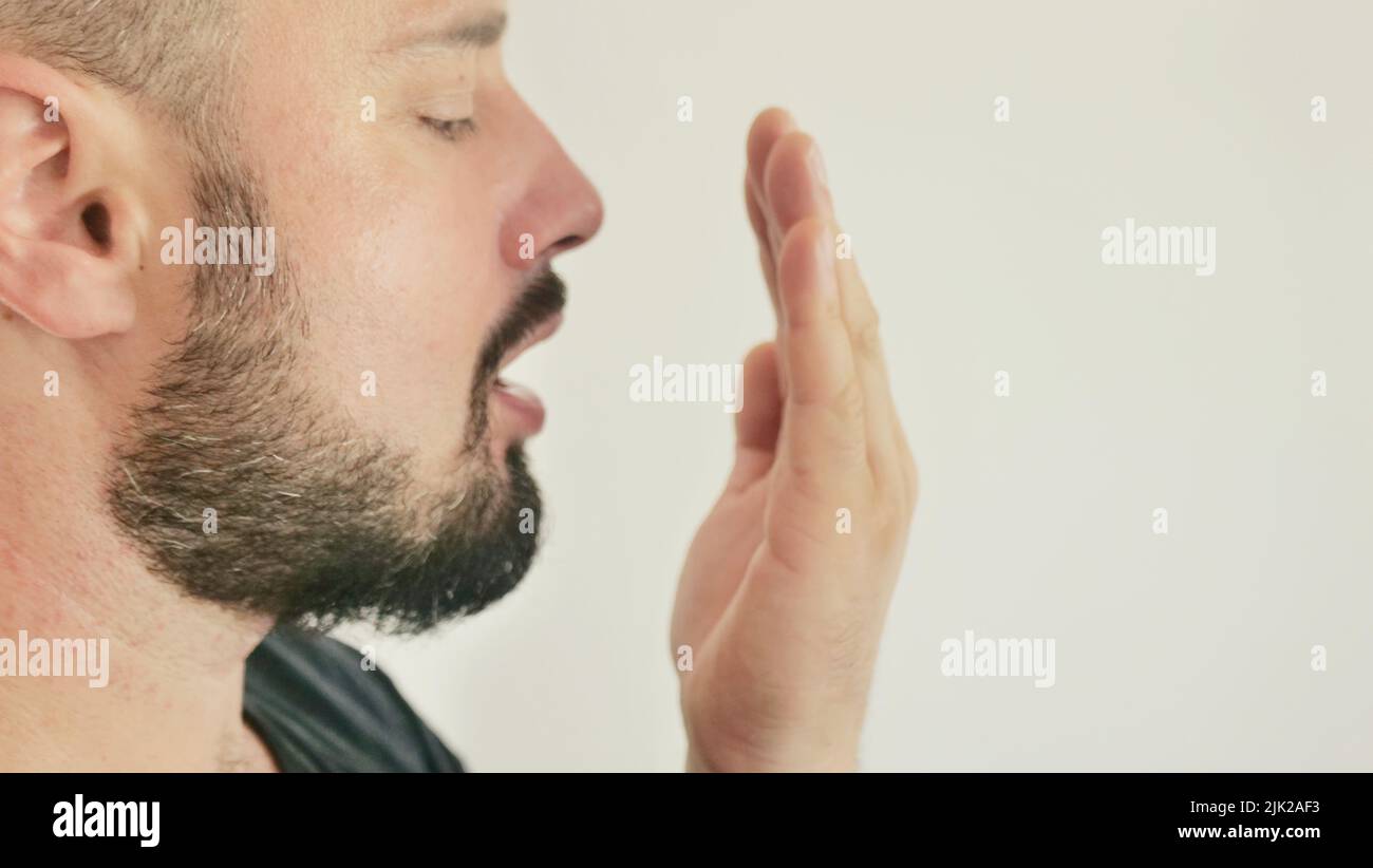 Mauvaise respiration. Le concept de l'halitose. Un jeune homme vérifie son souffle avec sa main Banque D'Images