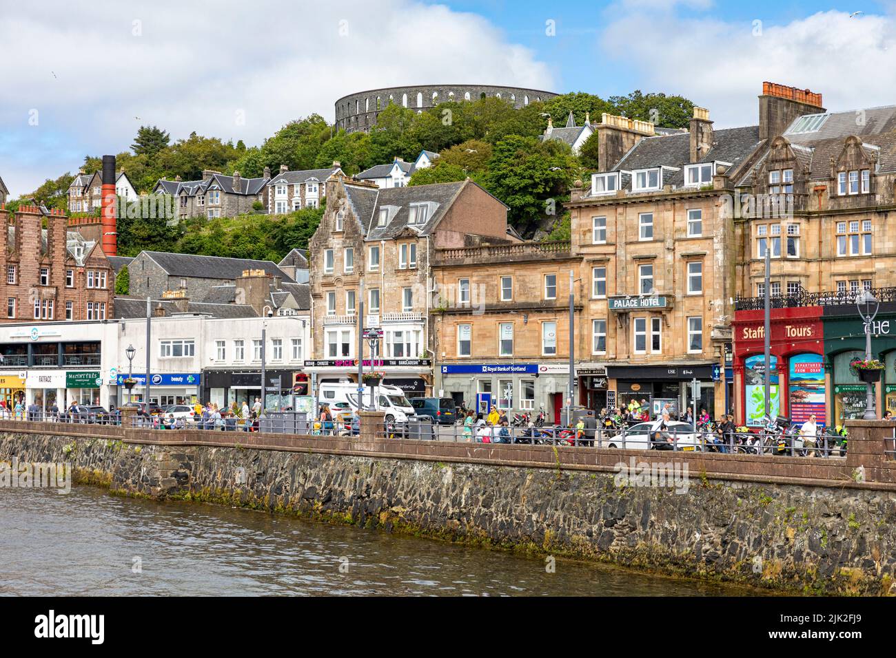 Centre-ville d'Oban le jour ensoleillé de l'été, les boutiques et les touristes dans la ville surplombaient la tour de McCaig, Oban, Argyll, Ecosse, Royaume-Uni Banque D'Images