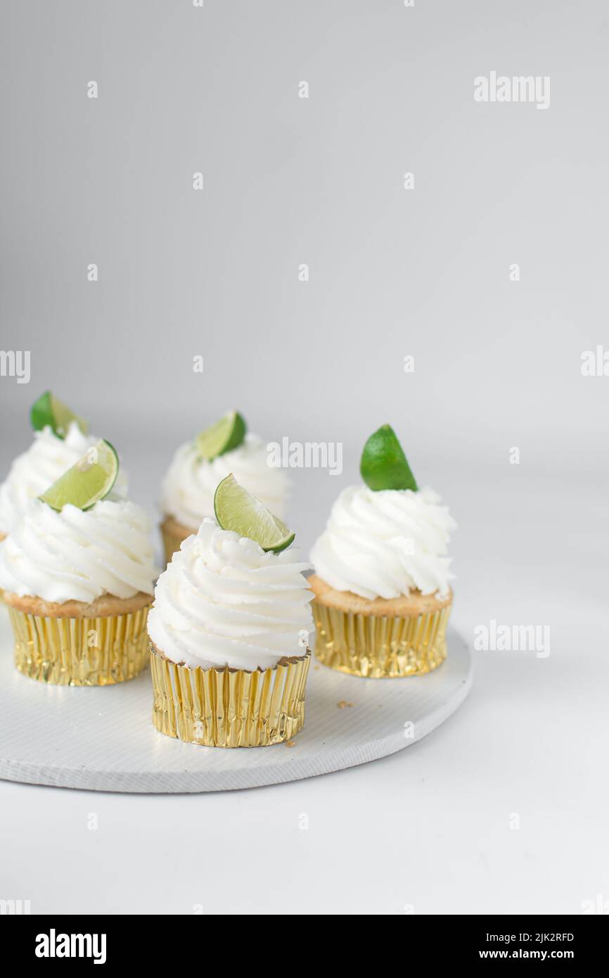 Cupcake au citron vert sur une table blanche, cupcake au citron vert avec crème blanche au beurre et un coin de citron vert, cupca à la margarita Banque D'Images