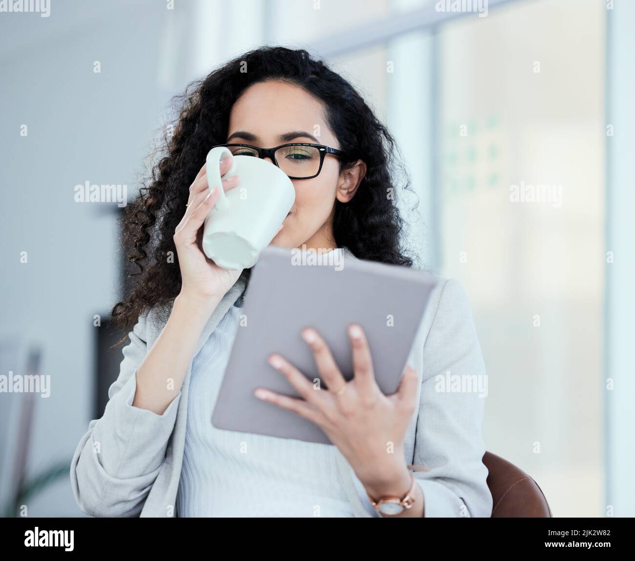 Je me demande comment je devrais répondre à cet e-mail. Une jeune femme d'affaires utilisant sa tablette numérique tout en buvant du café. Banque D'Images