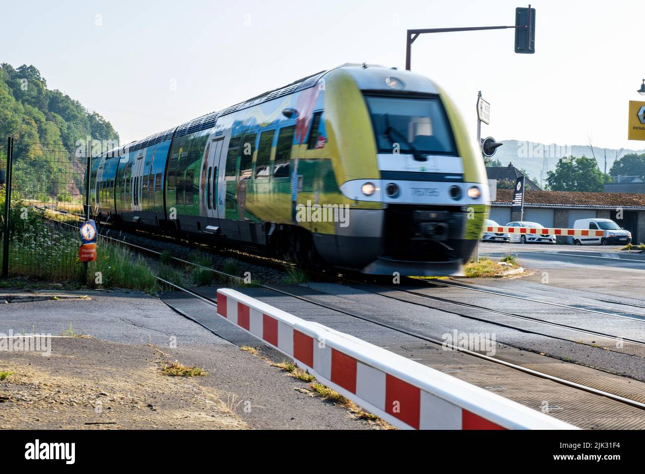 Train circulant en traversant une route, la barrière de sécurité est abaissée pour éviter le gazouillement des véhicules | train en passant une route de croisement Banque D'Images